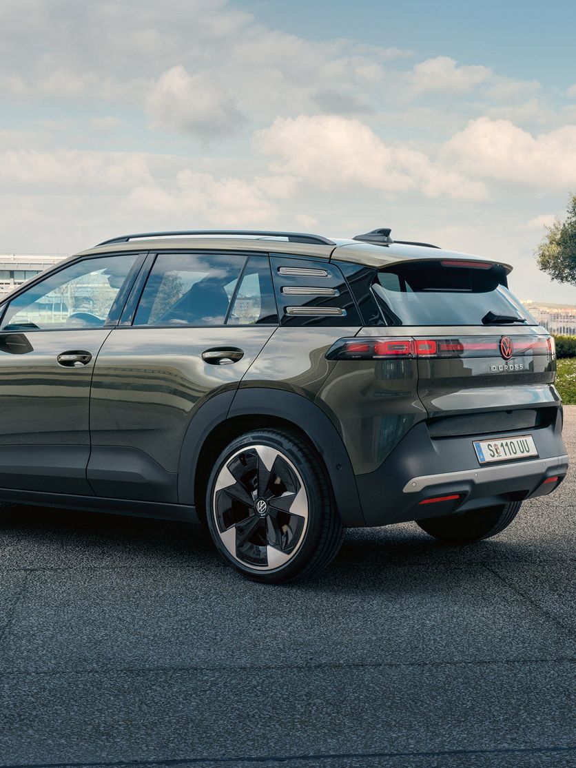 Изглед отзад на зелен VW ID. Cross, паркиран на площад със зелени дървета.