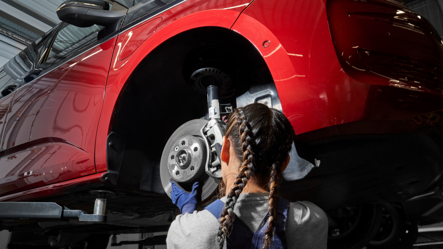Eine VW Mechanikerin wechselt die Bremsscheiben bei einem VW Nutzfahrzeug