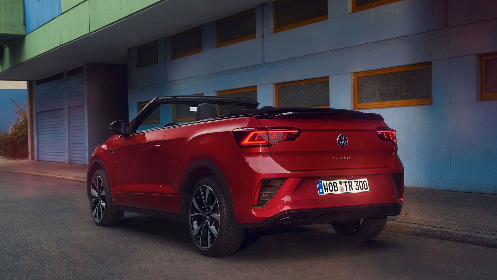 Ansicht des Hecks eines roten T-Roc Cabriolet mit geöffnetem Dach, parkend am Straßenrand. 