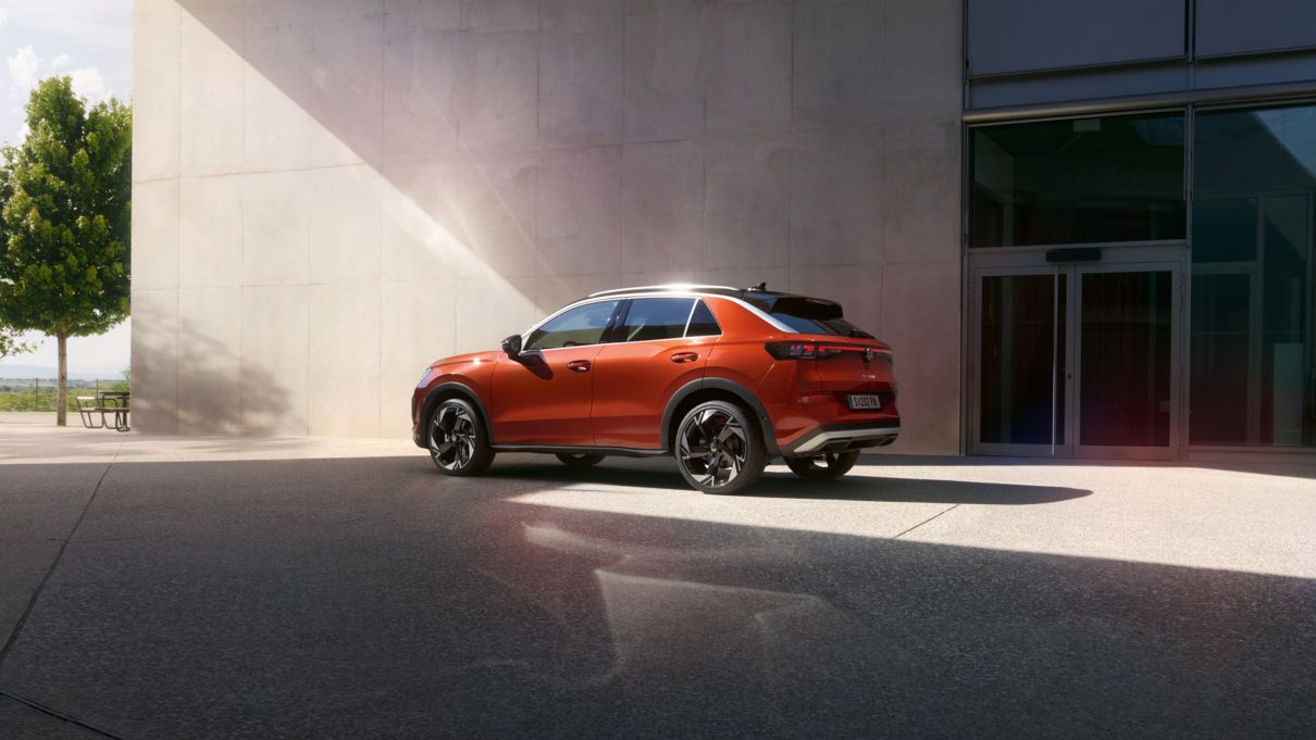 Червен Volkswagen T-Roc паркиран пред модерна сграда