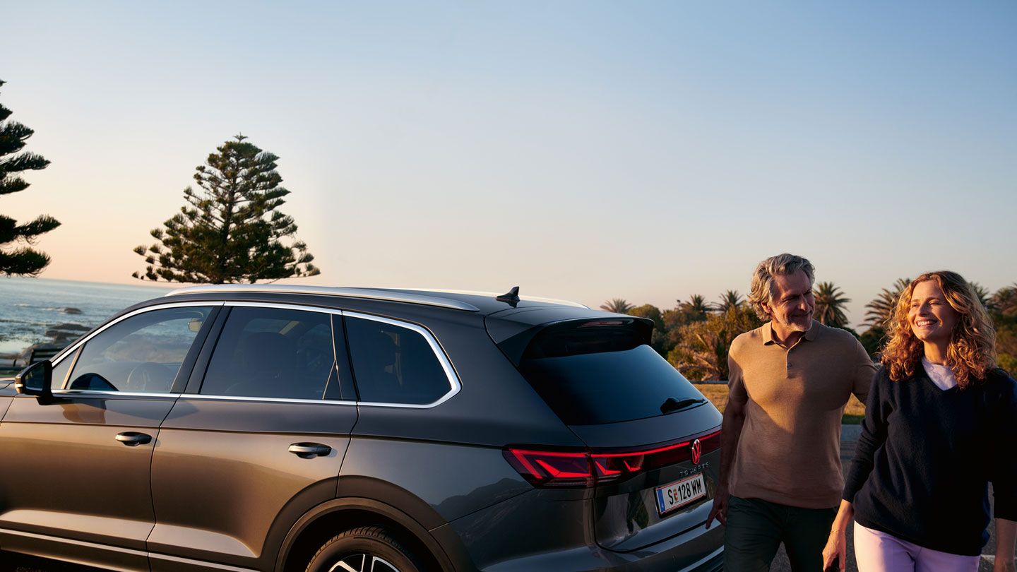 Мъж и жена минават покрай паркиран VW Touareg Elegance.