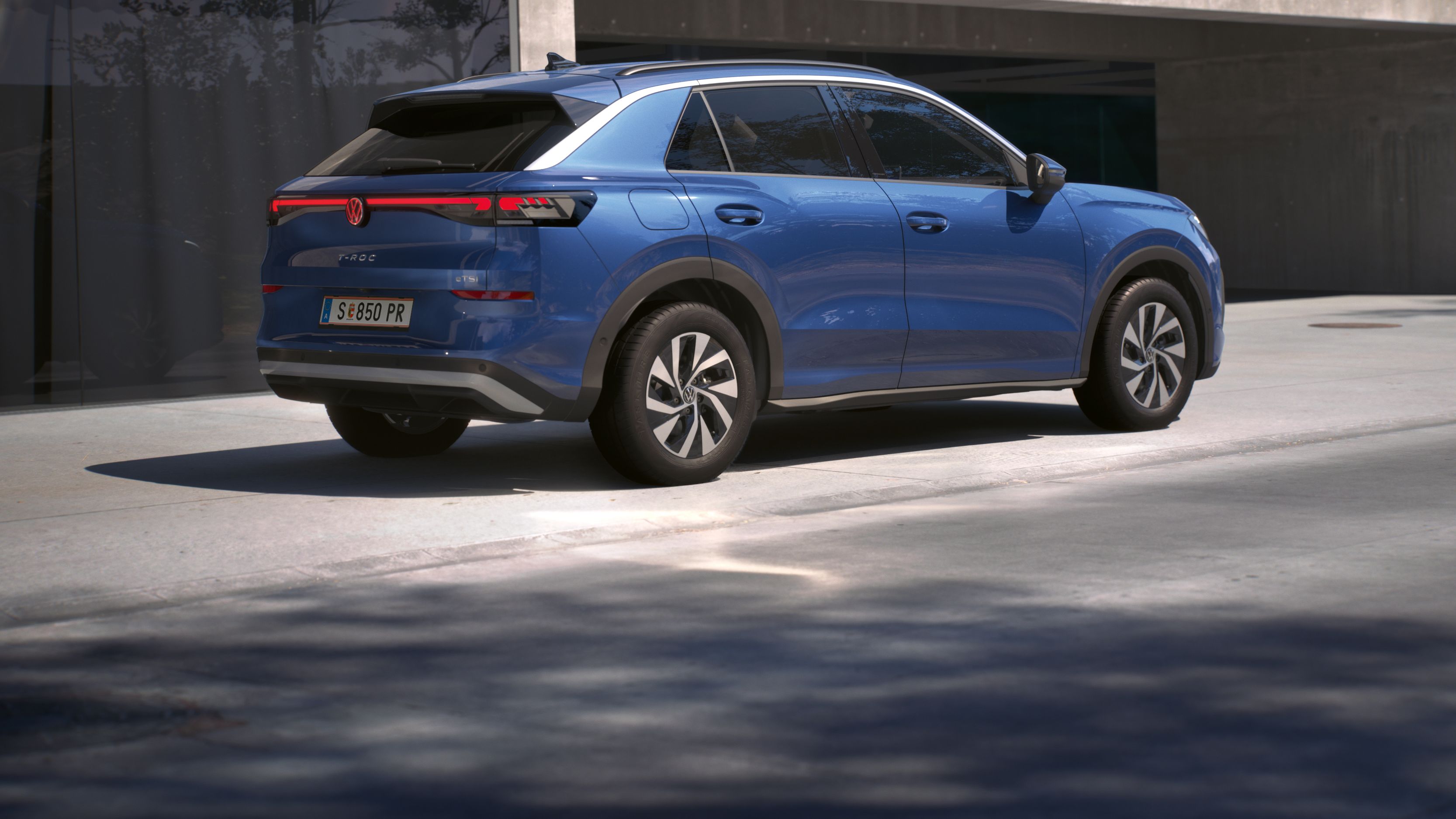 Син Volkswagen T-Roc, изглед отзад, с LED светлинна лента и модерен дизайн.